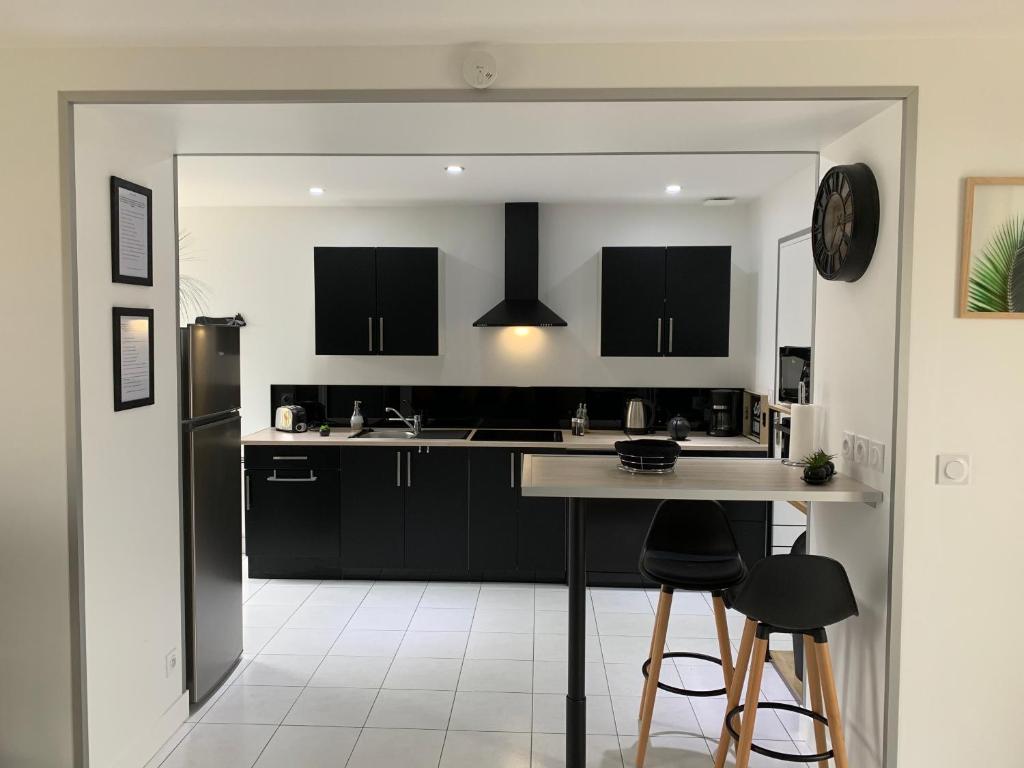 a kitchen with black cabinets and a black refrigerator at Gîte avec jardin à 1,5 km des plages du débarquement in Tracy-sur-Mer