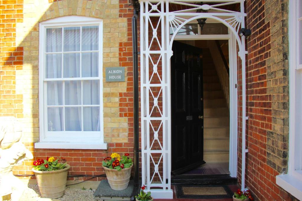 an open door to a brick house with two potted plants at Sleeps14 Seaside Luxury House on the Suffolk Coast in Saxmundham