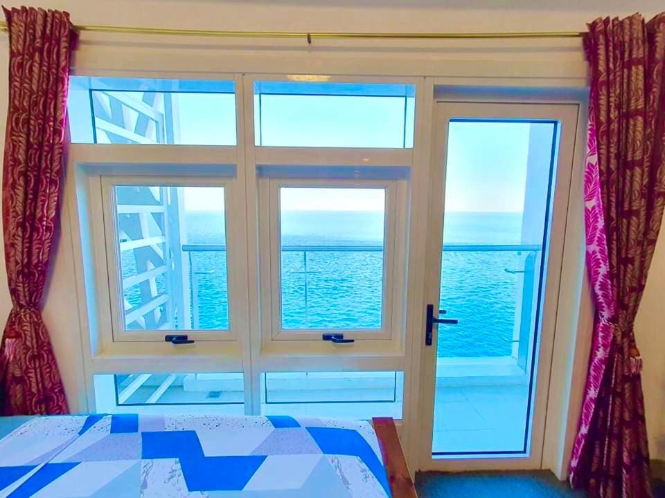 a bedroom with a window with a view of the ocean at Grand Condo-Hotel with Breathtaking Seaside Views in Lapu-Lapu, Cebu in Mactan