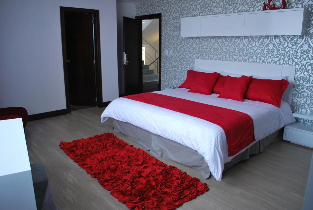 a bedroom with a large bed with red pillows at Rioné Hotel Boutique in Cuenca