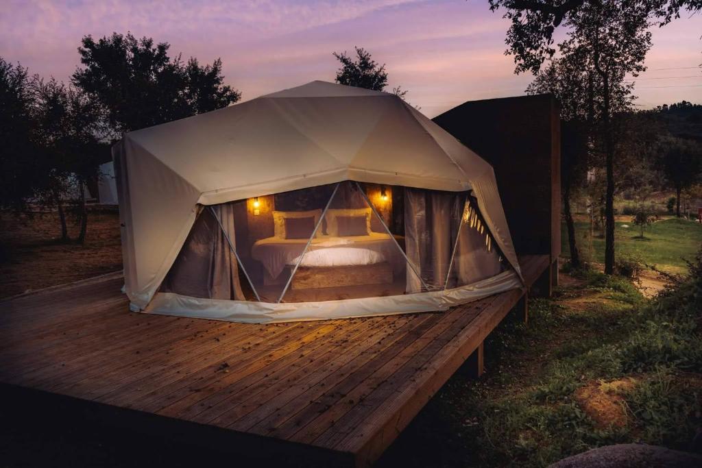 a tent with a bed in it on a wooden deck at Gavião Nature Village in Gavião