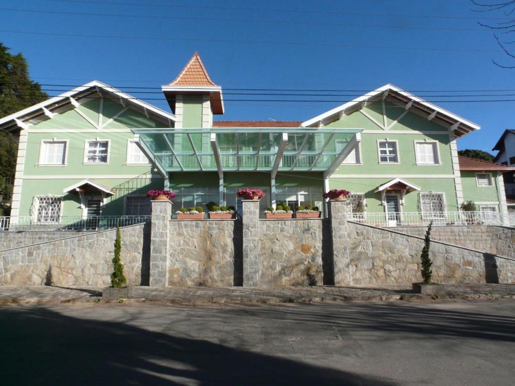 a green house with a fence in front of it at Hotel Casa São José in Campos do Jordão