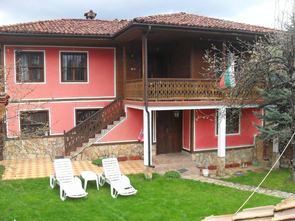 una casa roja con dos sillas de jardín en el patio en Borimechkova Kashta, en Koprivshtitsa