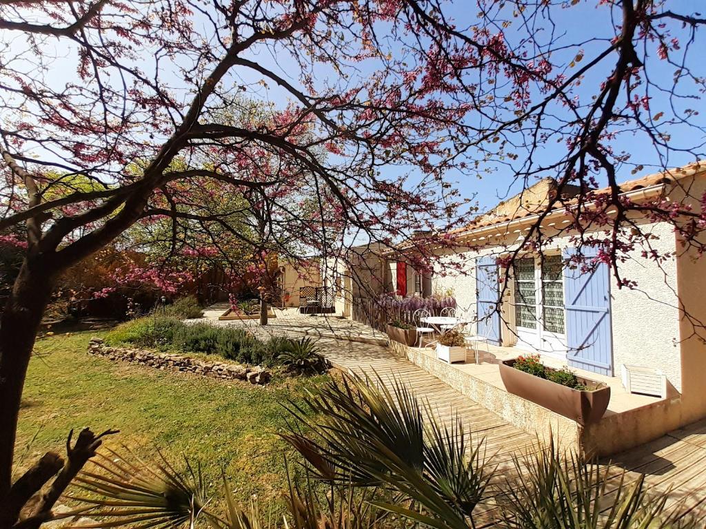 una casa blanca con un patio con un árbol en Logis Hôtel Restaurant Le Clos des Capitelles, en Uchaud