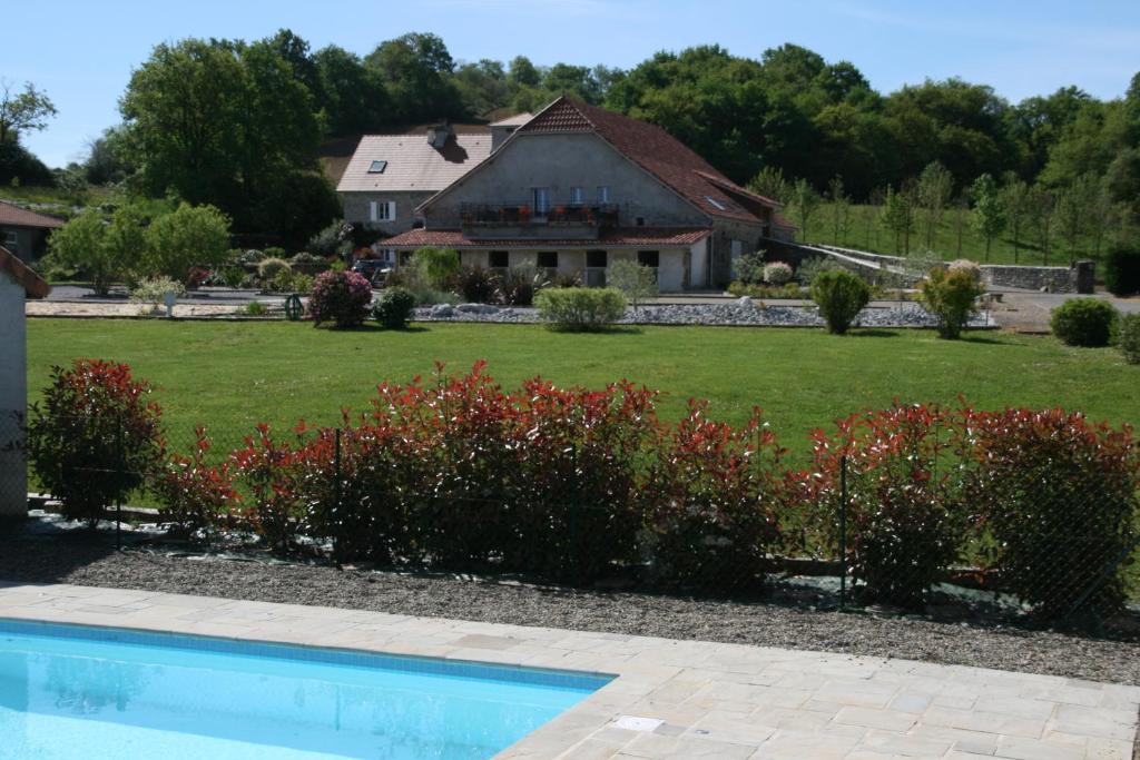 une maison et une cour avec une piscine et des fleurs dans l'établissement Manoir Théas, à Barraute-Camu