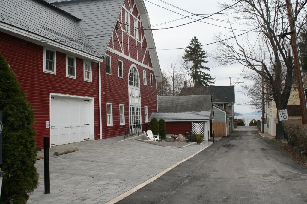 um celeiro vermelho com uma entrada em frente a uma casa em Visions Inn em Cooperstown