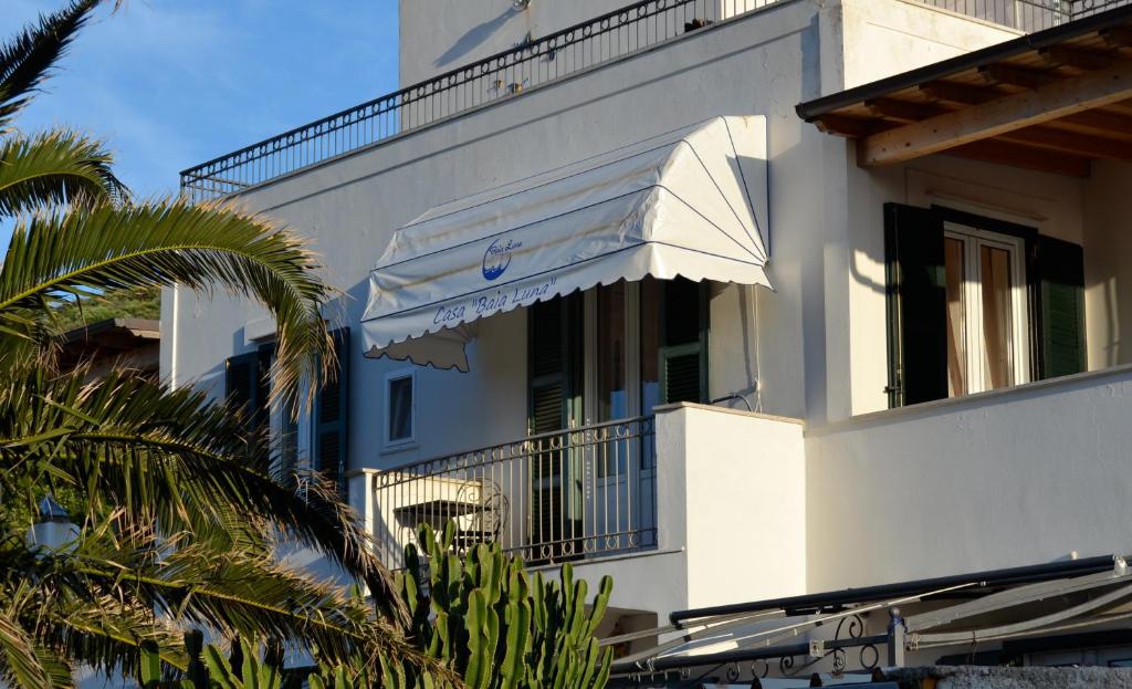 a white building with a balcony and a palm tree at Casa Baia Luna in Ponza