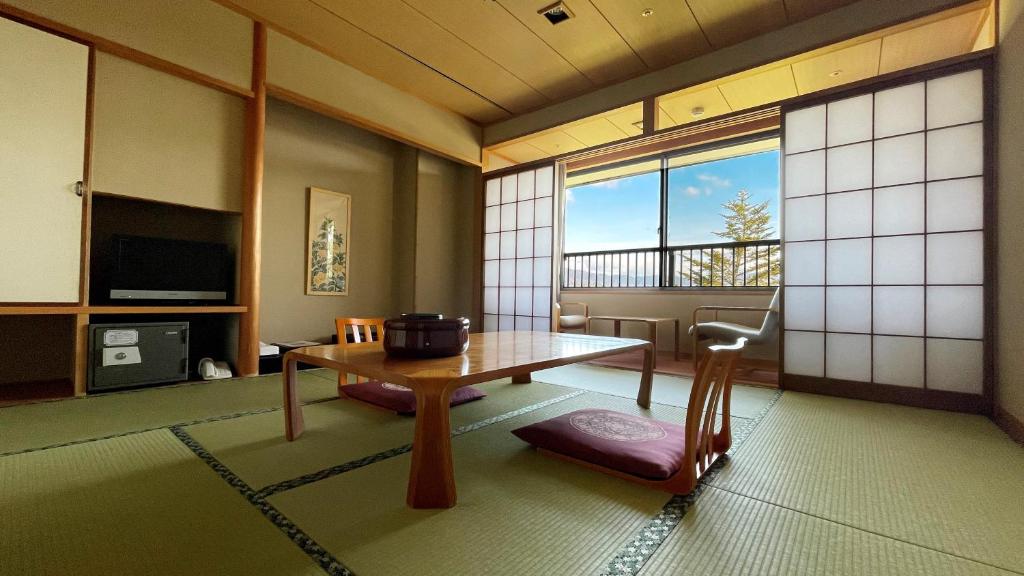 a living room with a table and a window at Miyajima Morinoyado in Miyajima