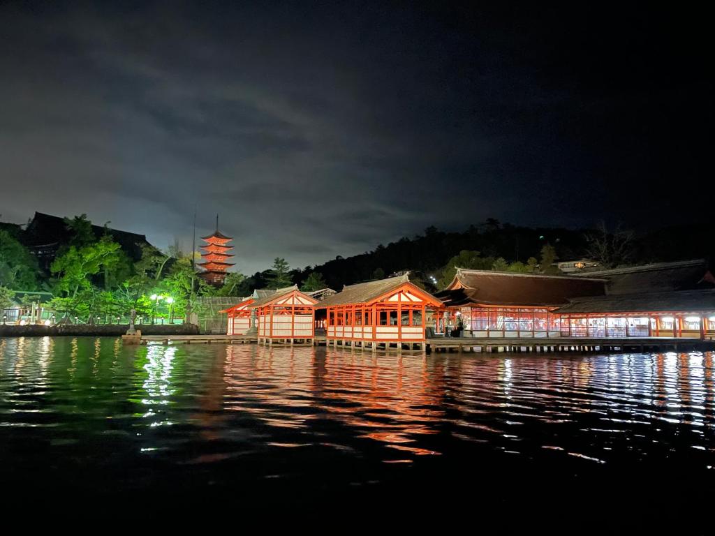 a building sitting on the water at night at Miyajima Morinoyado in Miyajima