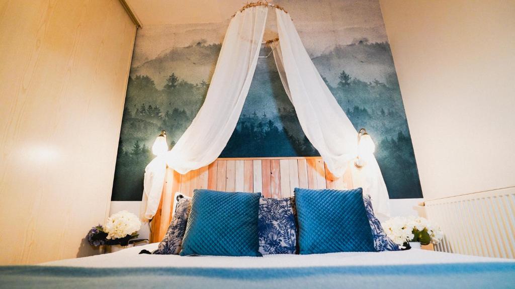 - une chambre avec un lit à baldaquin et des oreillers bleus dans l'établissement La Lavandière upcycling, confort, fibre BedinShop, à Romans-sur-Isère