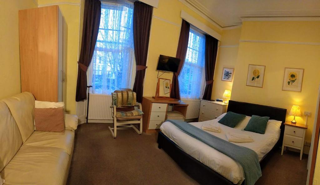 a bedroom with a bed and a couch and windows at Haven House in Torquay