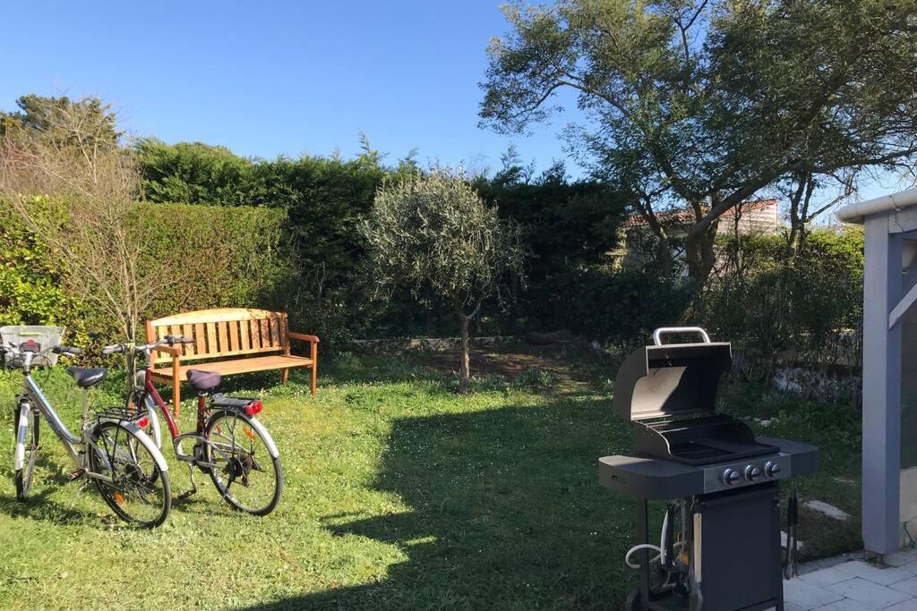- un barbecue et un vélo garé dans une cour dans l'établissement Maison de vacances 2 chambres wifi à 400 m de la plage, à Les Moutiers