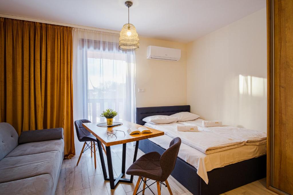 a bedroom with a bed and a table and a couch at Apartamenty Homole in Szczawnica