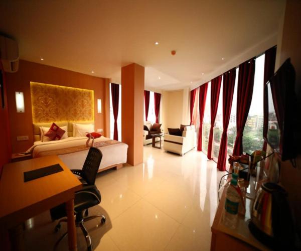 una camera d'albergo con letto, scrivania e sedie di THE RED VELVET HOTEL a Patna