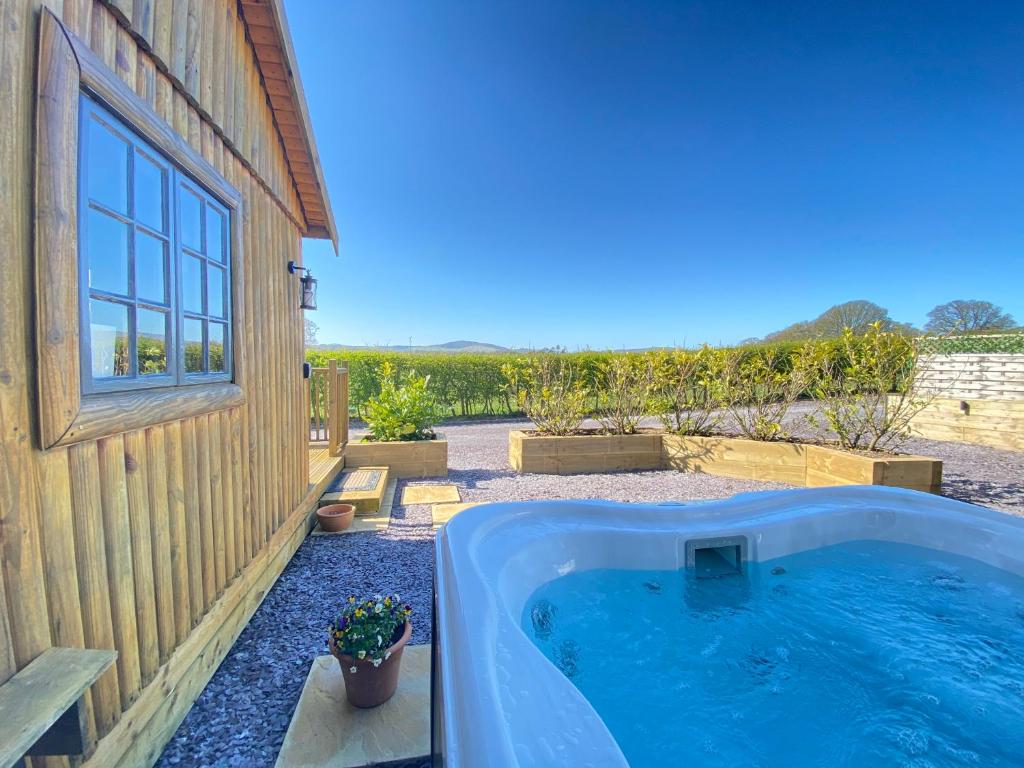 a hot tub sitting next to a building with a yard at Sunset Cabin in Mold