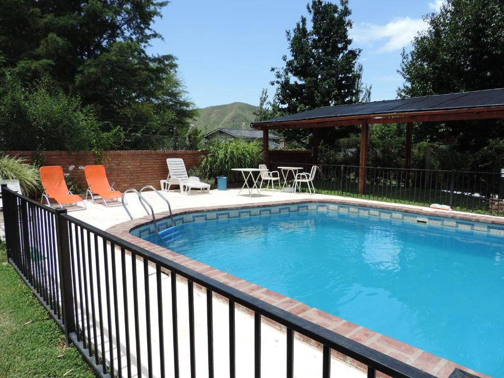 una piscina con sillas naranjas y una valla en Hotel Samay Huasi en Villa General Belgrano