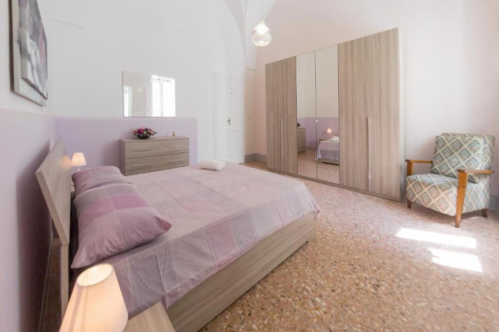 1 dormitorio con cama, silla y espejo en Casa Vacanze Penelope, en Alessano