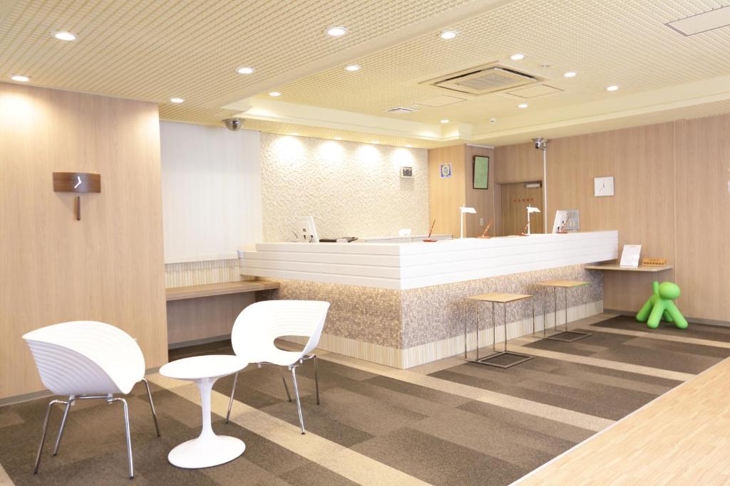 une salle d'attente avec des chaises blanches et un comptoir de réception dans l'établissement Hotel Green Mark, à Sendai