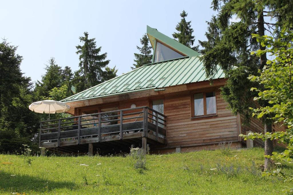 Cabaña de madera con techo verde y sombrilla en Les Loges du Jura 4 étoiles, en Prénovel