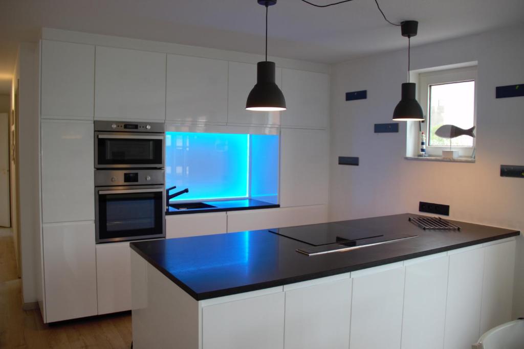 cocina con armarios blancos y encimera azul en Résidence Château Angélus, en De Haan