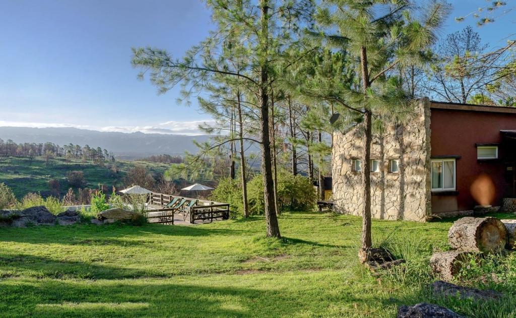 una casa en un campo con árboles en primer plano en Monte Barranco en Villa Yacanto