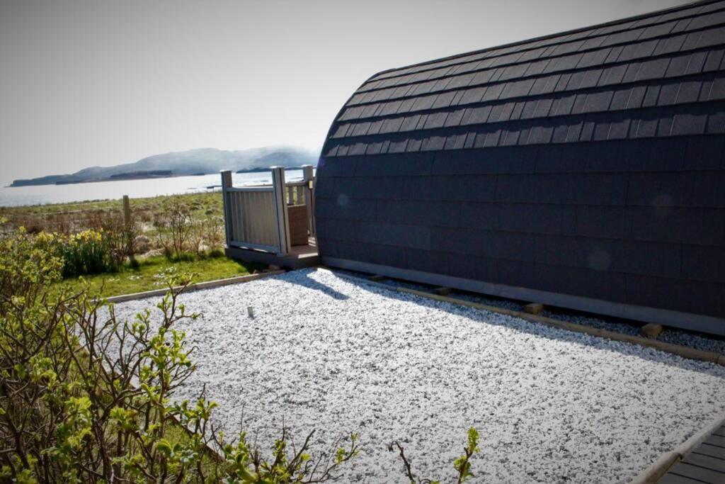 a building with a gravel yard next to a body of water at Ose Pod, an ever changing view to the sea in Ose