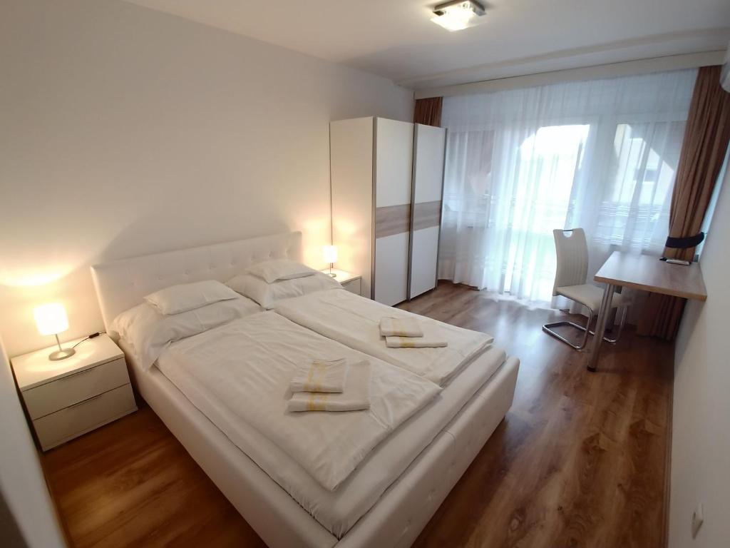 "ハルカーニャ"にあるEMMA Apartman Harkányのベッドルーム1室(白いベッド1台、タオル2枚付)