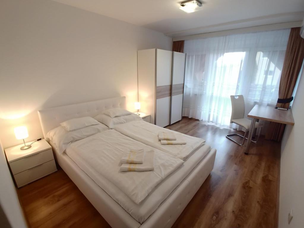 sypialnia z białym łóżkiem i 2 ręcznikami w obiekcie EMMA Apartman Harkány w mieście Harkány