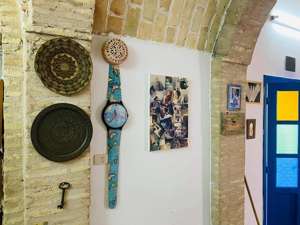 a clock hanging on a wall with pictures on it at Maison d'hôte Chama in Kairouan