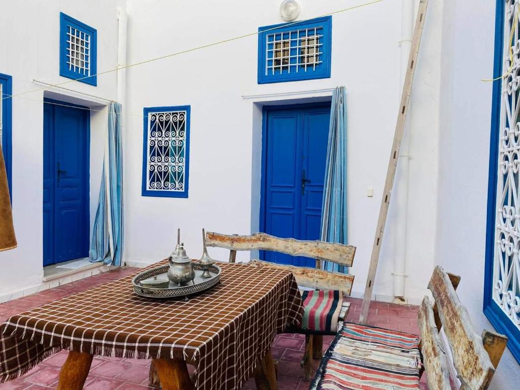 a table and chairs in a room with blue doors at Maison d'hôte Chama in Kairouan
