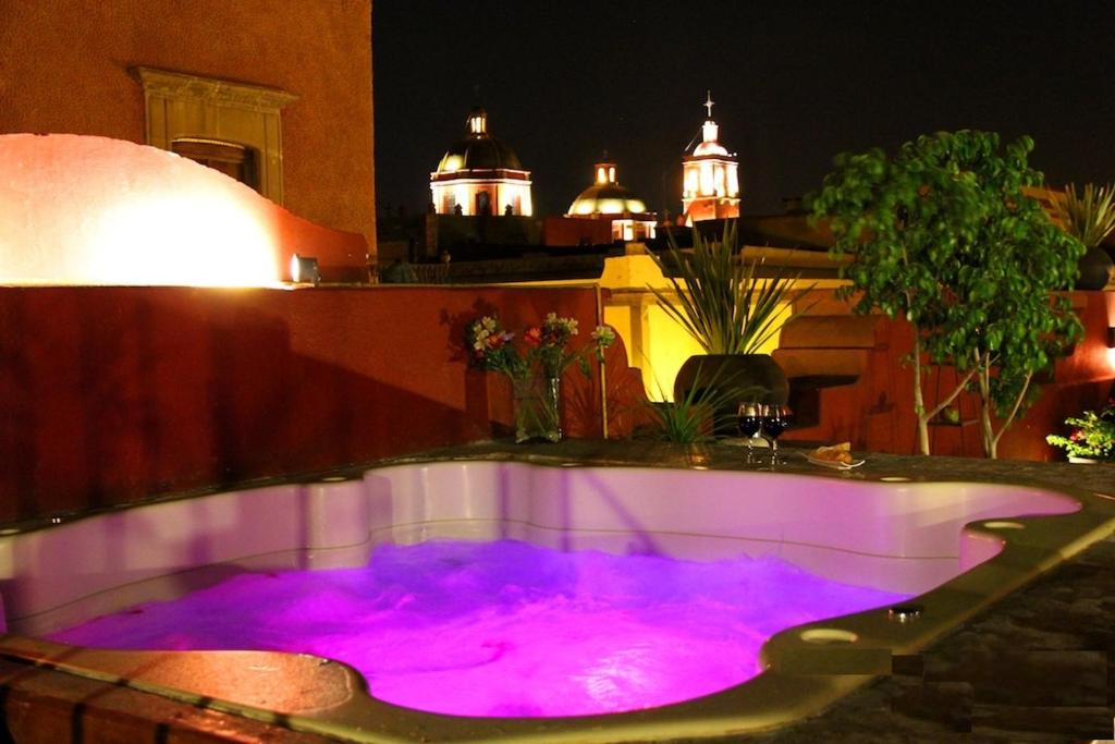 uma banheira de hidromassagem com iluminação roxa num quintal à noite em La Casa del Naranjo Hotel Boutique em Querétaro