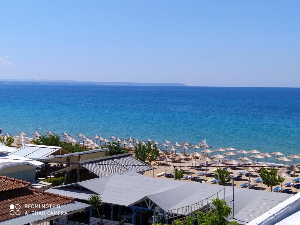 een uitzicht op een strand met parasols en de oceaan bij Hause Zorbas in Paralia Dionysiou