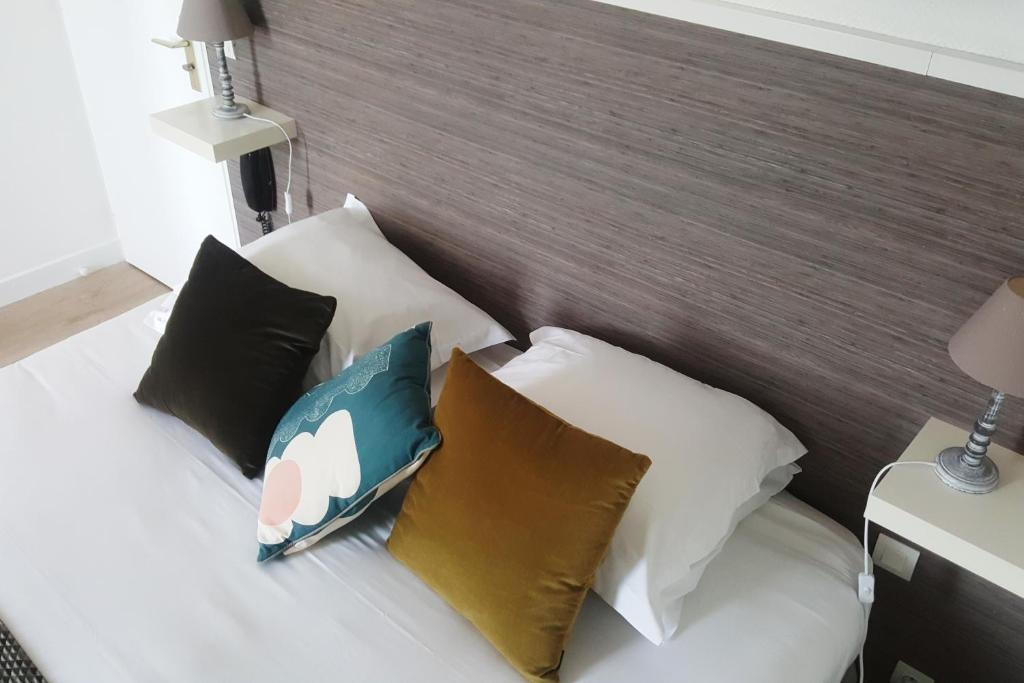 a bedroom with a bed with four pillows at Hotel De L'Europe in Perros-Guirec