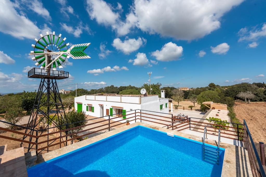 ein Haus mit einer Windmühle und einem Pool in der Unterkunft Son Vorera, situada en una colina, con piscina. in Es Carritxo