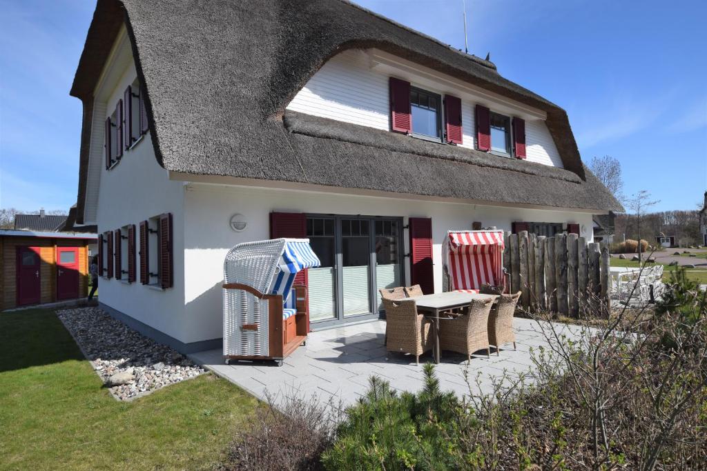a white house with a table and chairs at Dat Smucke Huus - 6 Personen strandnah unter Reet in Boltenhagen - 3 SZ - Finnische Sauna - 2 Strandkörbe - Strand 650m in Boltenhagen