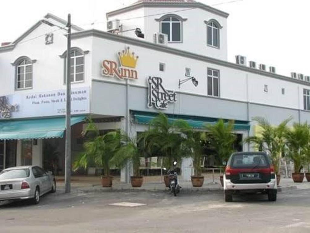 duży biały budynek z samochodami zaparkowanymi na parkingu w obiekcie SR Inn w mieście Simpang Renggam