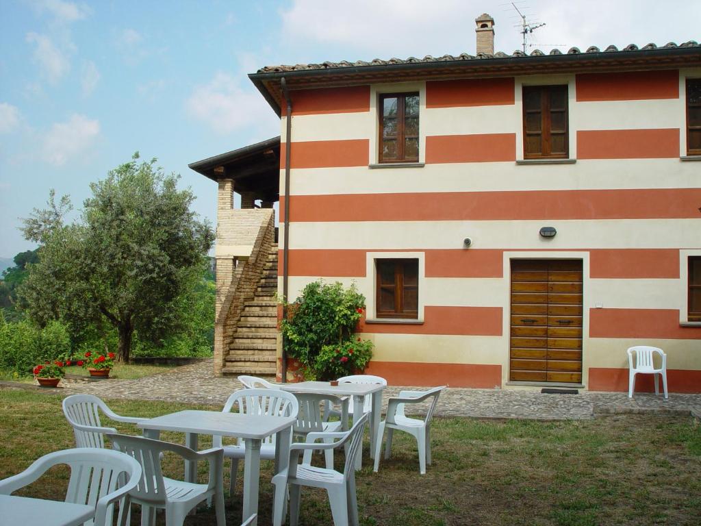 una casa con mesas blancas y sillas delante de ella en Poggio di Villa Fano, en Citerna