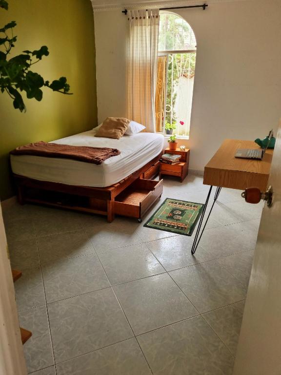 a bedroom with a bed and a table and a window at Tatami Hostel in Bucaramanga