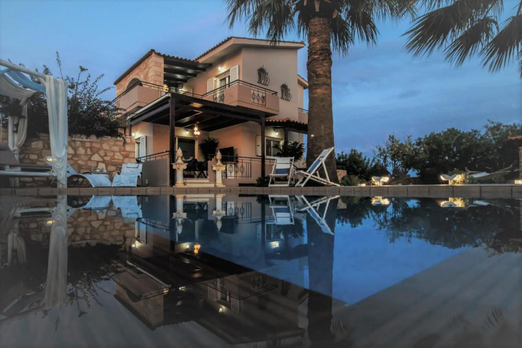 a house with a palm tree next to a swimming pool at Villa SAR in Kampani Chania in Kambánion