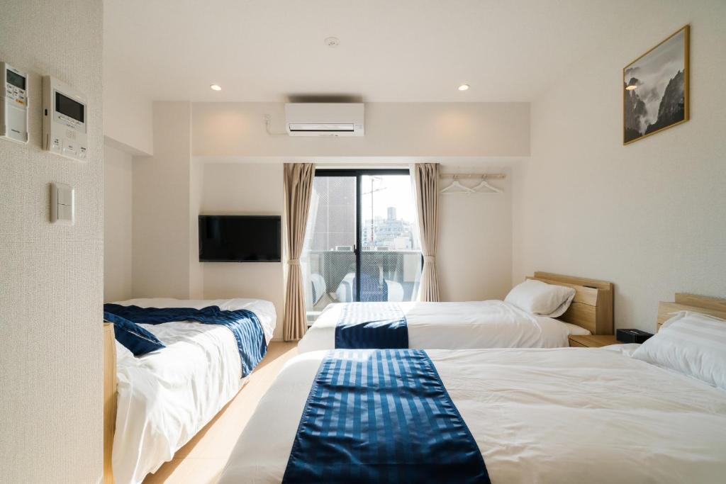 a hotel room with three beds and a window at Hotel Emir in Tokyo