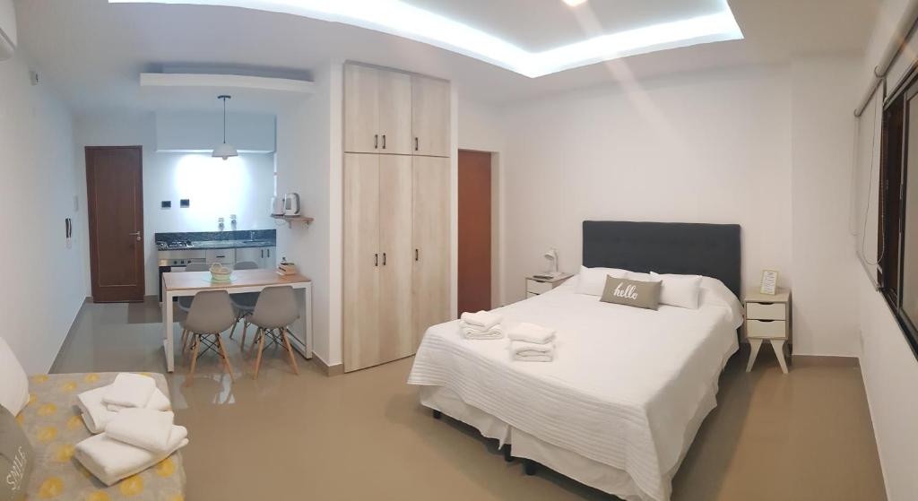 a white bedroom with a bed and a kitchen at Patagonia Apart in Paraná