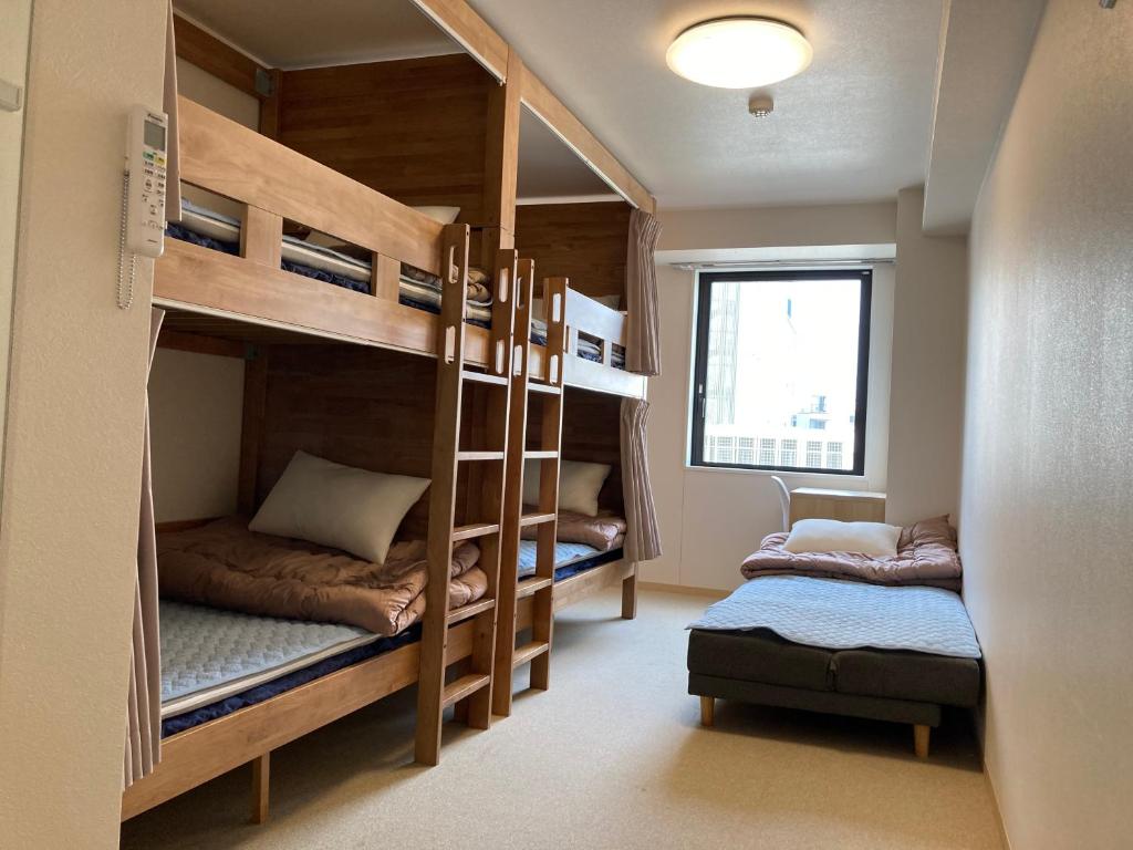 Pokój z łóżkiem piętrowym z 2 łóżkami piętrowymi i krzesłem w obiekcie Tokyo Ueno Youth Hostel w Tokio