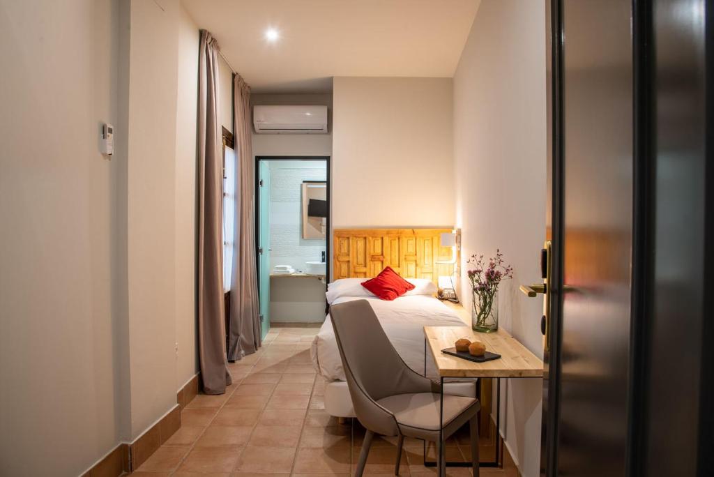 ein Schlafzimmer mit einem Bett und einem Tisch mit einem Stuhl in der Unterkunft Palacio San Fernando in Utrera