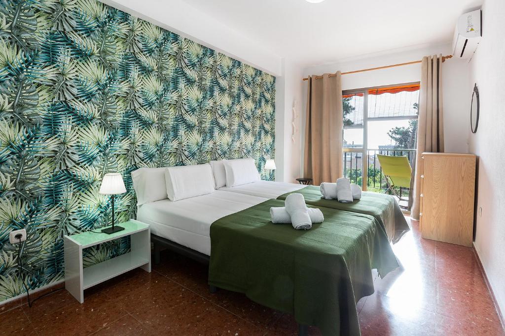 a bedroom with a white bed and a green wall at MONKÓ CACTUS in Torremolinos