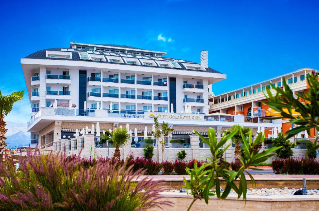 un gran edificio blanco con palmeras delante en White Gold Hotel & Spa, en Alanya