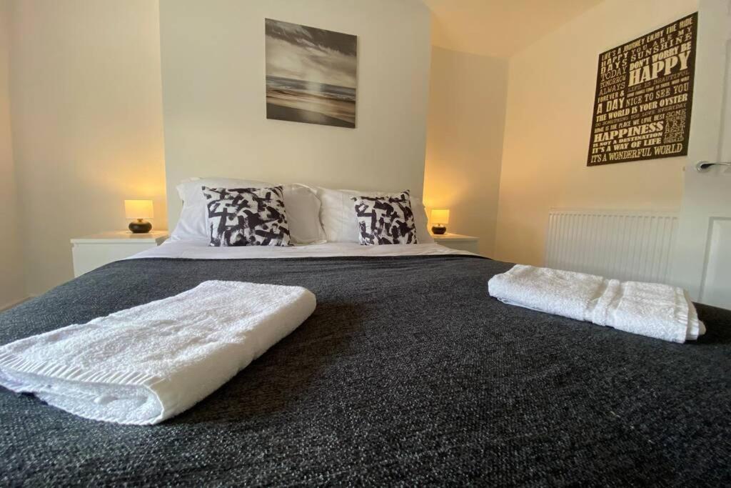 a large bed in a bedroom with two lamps at Contemporary 2 Floor Flat with Sea Views! in Lowestoft
