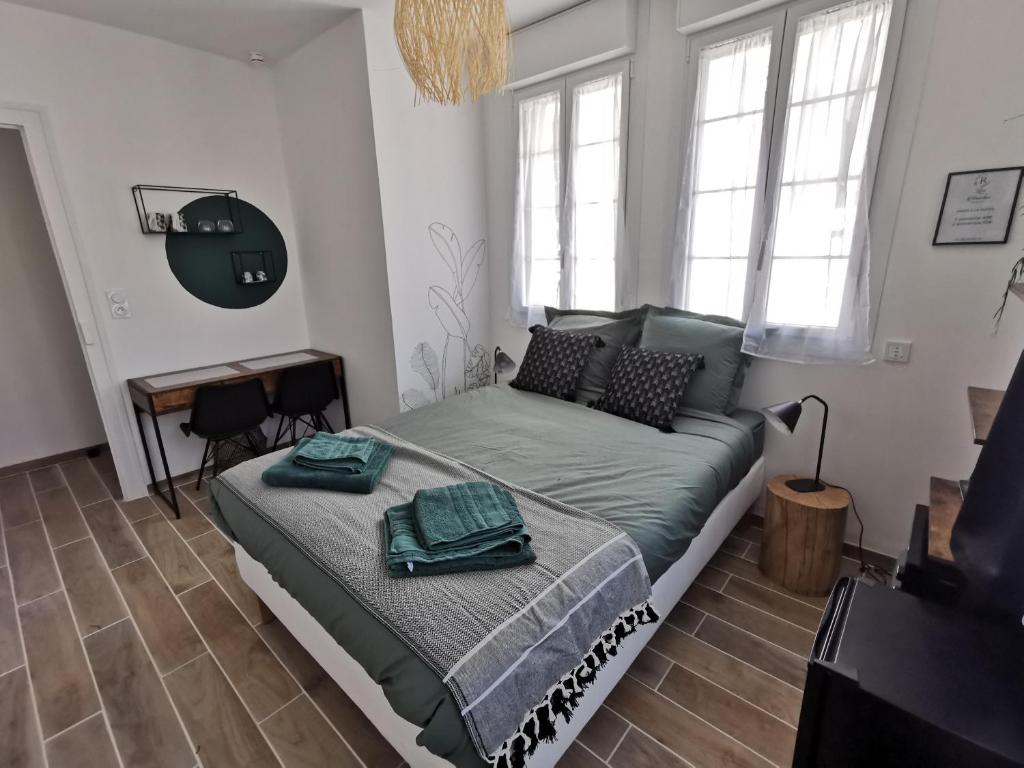 um quarto com uma cama, uma secretária e janelas em Les Rauches - Quai Loire - Chambre Jungle em Châteauneuf-sur-Loire