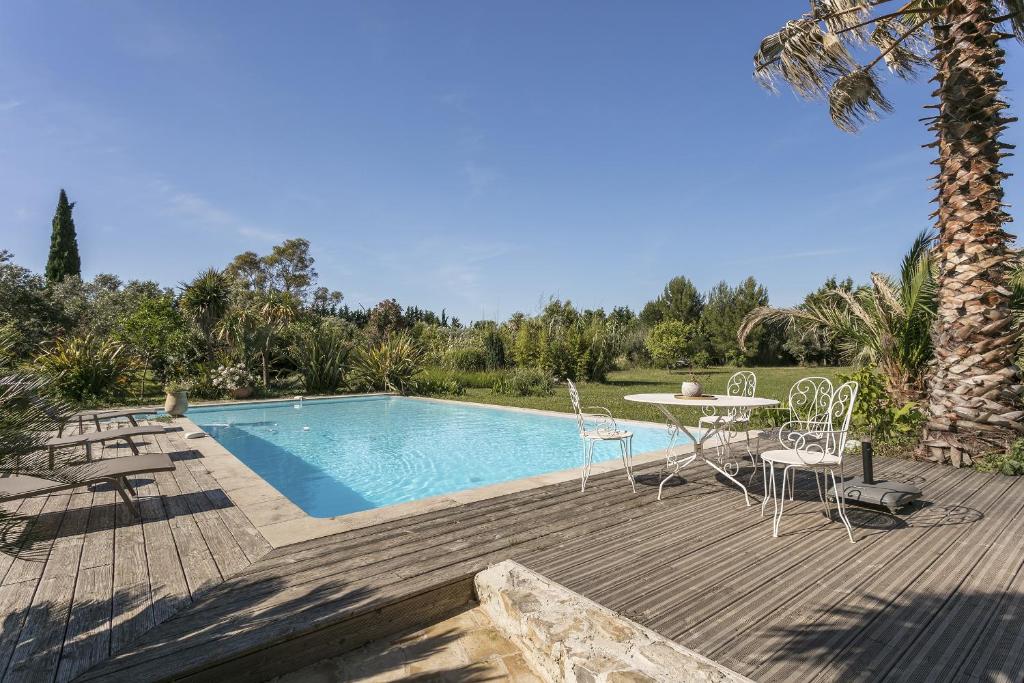 um pátio com uma mesa e cadeiras ao lado de uma piscina em Domaine Sesquier Mas d'exception Hibiscus em Mèze