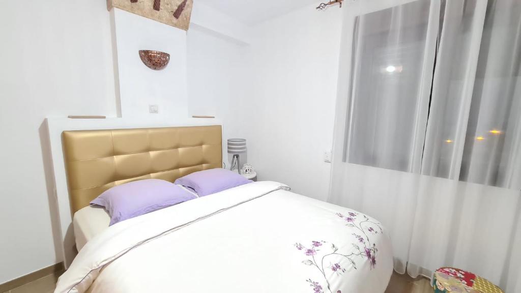 sypialnia z łóżkiem z fioletowymi poduszkami i oknem w obiekcie Sunny Seaside Escape in Aguadulce w mieście Aguadulce