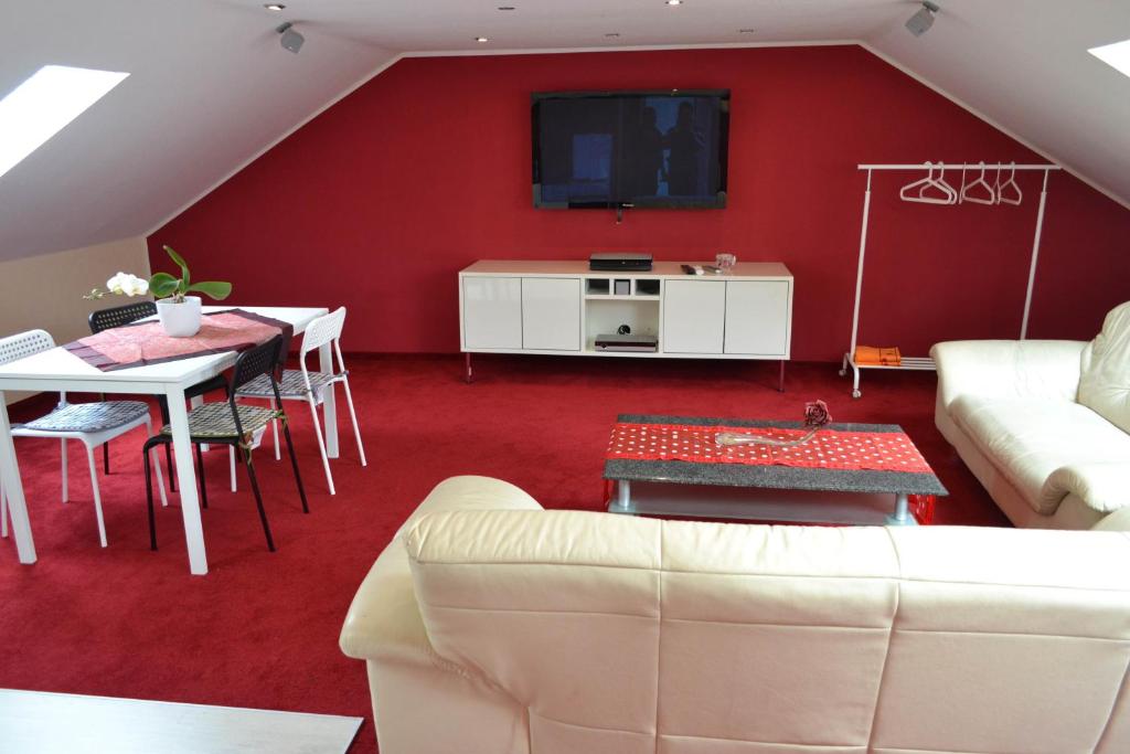 プルハイムにあるロフト アパートメンツ プルハイムのリビングルーム(ソファ、赤い壁のテレビ付)
